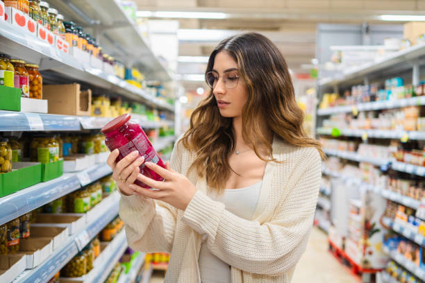 Person reading food labels in a supermarket aisle